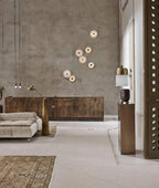 Clérachic six sconces clustered on a grey plaster wall above a burnished metal sideboard in a living room.
