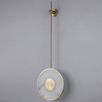 The disc lit on a plain grey wall, warm light haloing out around the alabaster.
