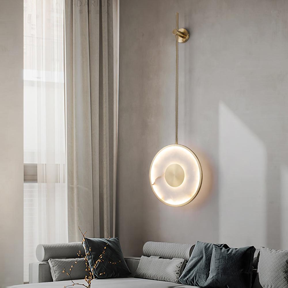Lit above a grey sofa beside a curtained window, branches in a glass vase below.