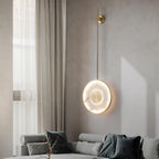 Lit above a grey sofa beside a curtained window, branches in a glass vase below.