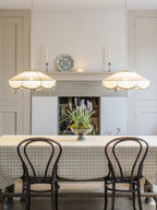 Two of this Clérachic pendant hang above a gingham-clothed table set with bentwood chairs, near a stone fireplace.