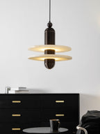 Dark bronze Saturn pendant lit above a long black sideboard, showing the drop from ceiling to disc