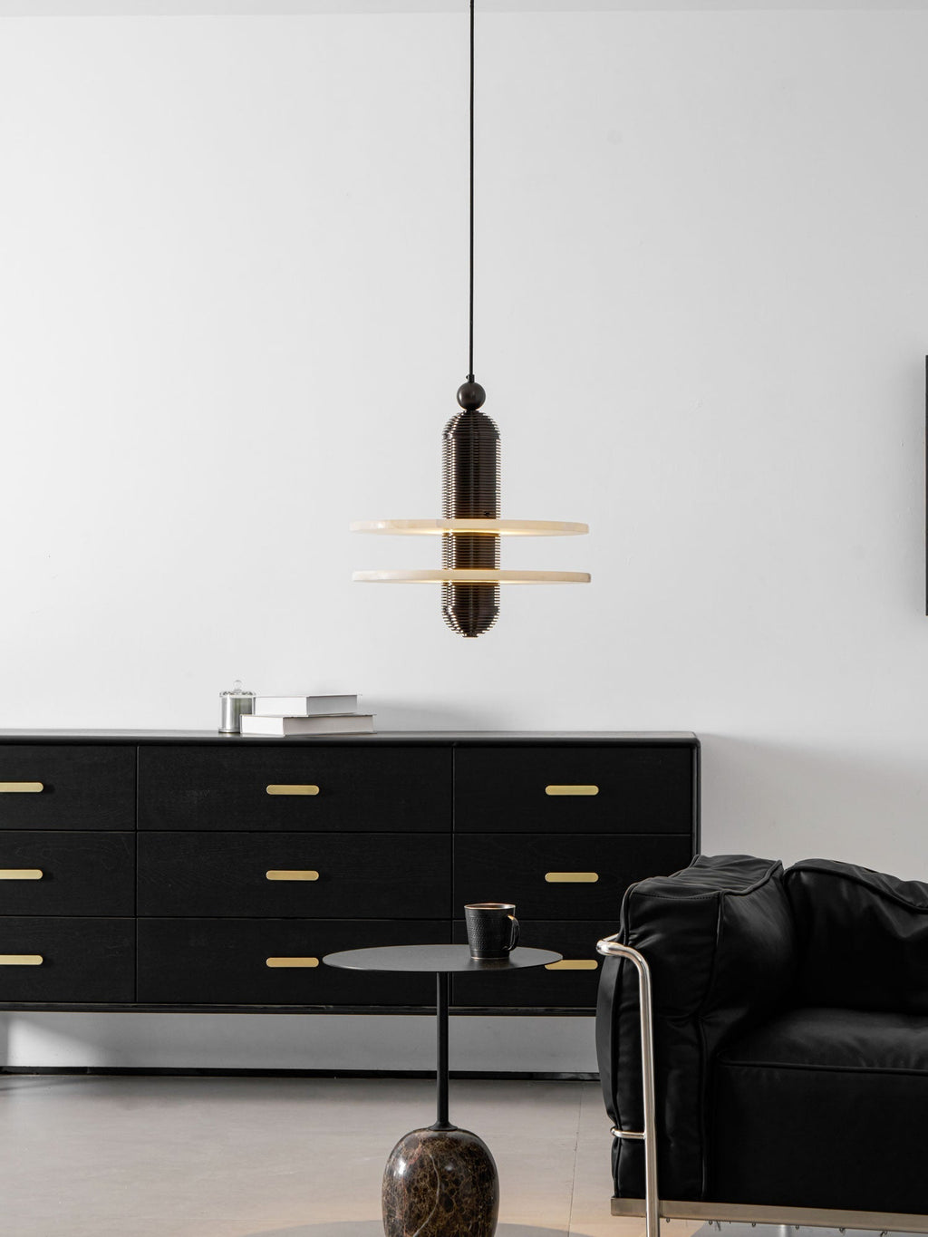 Room view of the dark bronze Saturn pendant hung over a sideboard and a leather armchair