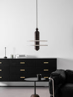 Wide interior view with the dark bronze Saturn pendant above a black sideboard and low side table