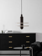 Dark bronze Saturn pendant with two alabaster discs above a black oak sideboard, seen from a distance