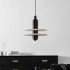 Dark bronze Saturn pendant unlit, its wide alabaster discs framed against a plain white wall