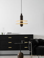 Saturn pendant in dark bronze lit above a black sideboard, glow caught under both stone discs
