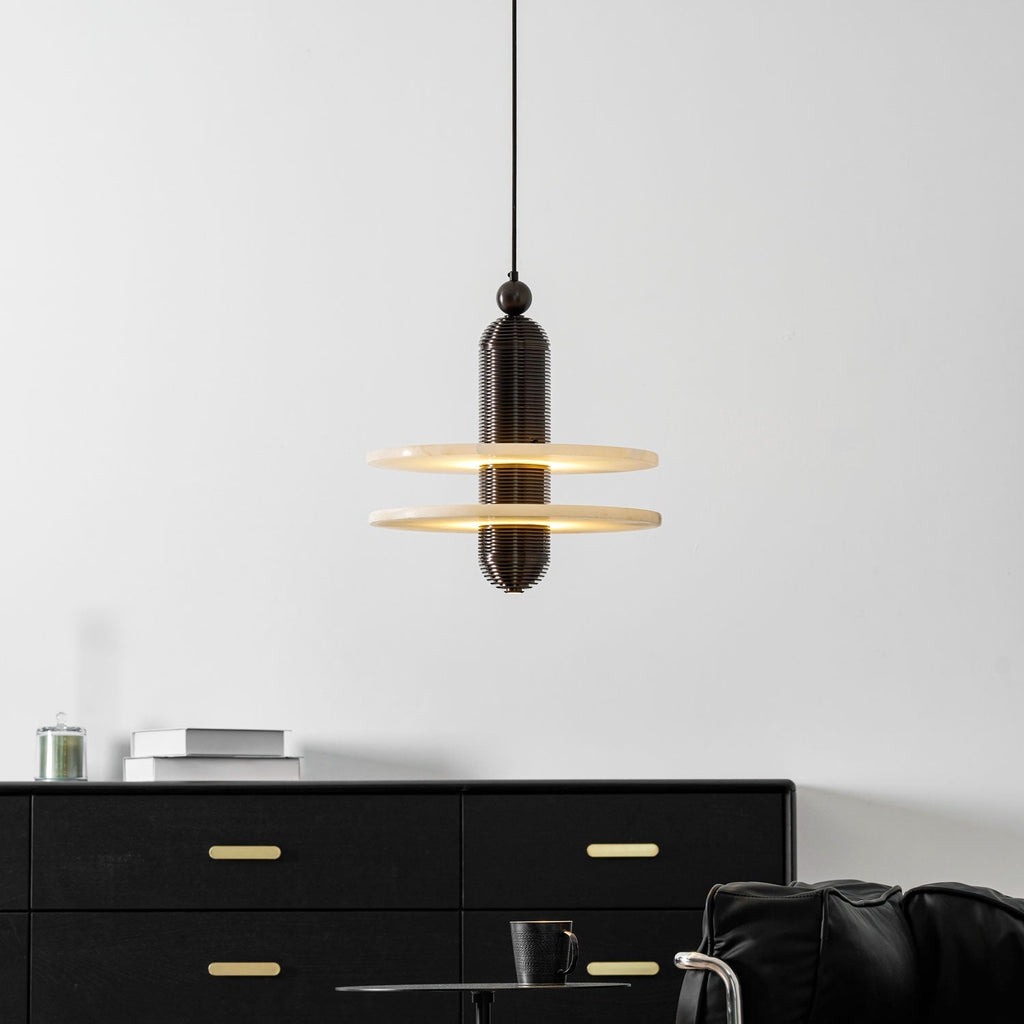 Dark bronze Saturn pendant centred on a white wall, light spilling from between the two discs