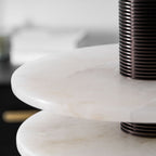 Close crop on the two alabaster disc edges where the ribbed bronze column passes through them