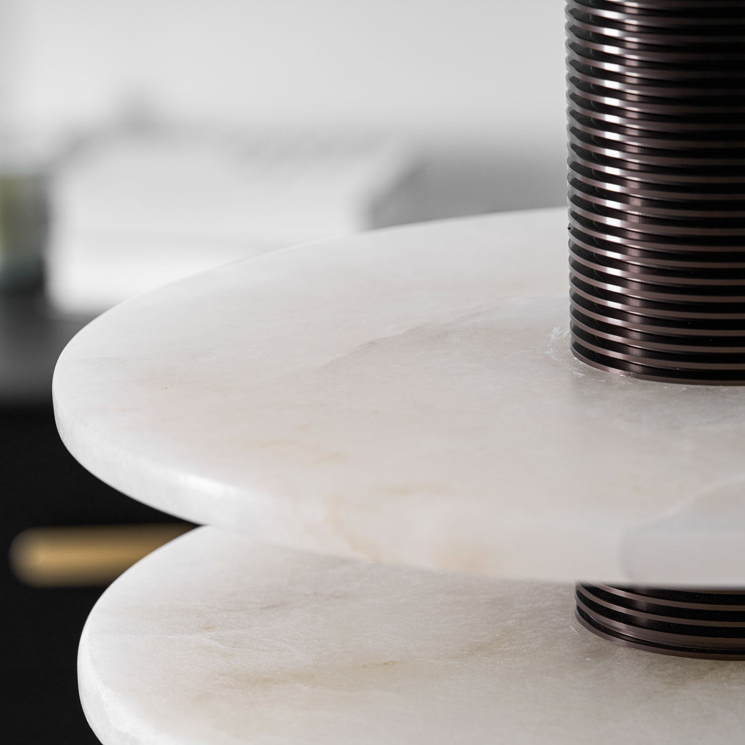 Close crop on the two alabaster disc edges where the ribbed bronze column passes through them