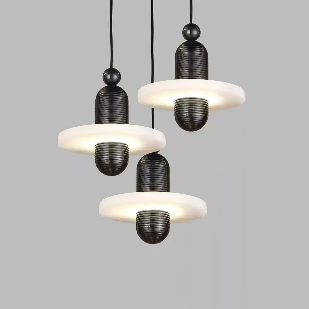 Cluster of three black Orion pendants hung at staggered heights, alabaster discs glowing.