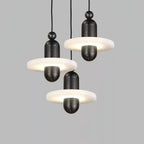 Cluster of three black Orion pendants hung at staggered heights, alabaster discs glowing.