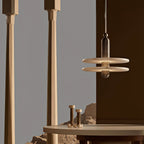 Gold two-disc Orion pendant hanging over a round table in a warm, column-lined room.