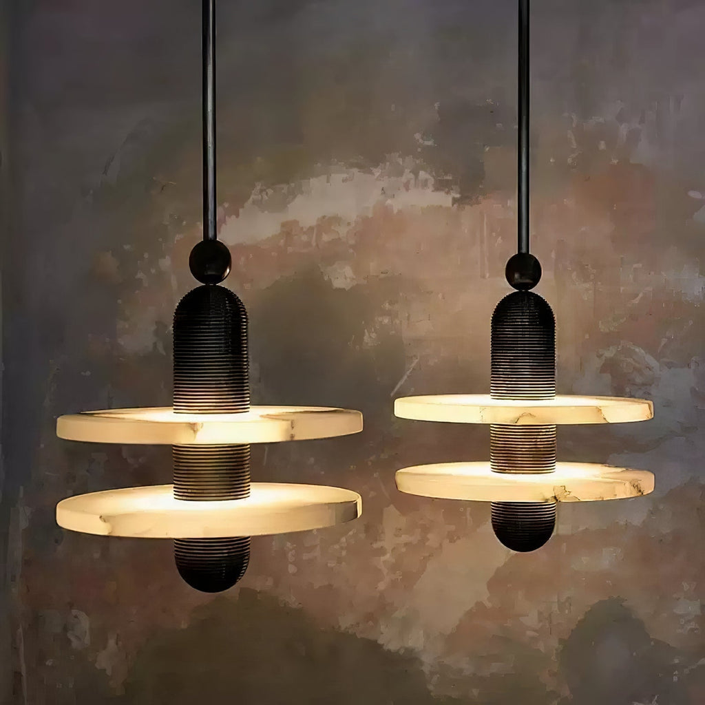 Two black two-disc Orion pendants glowing warm against a weathered plaster wall.