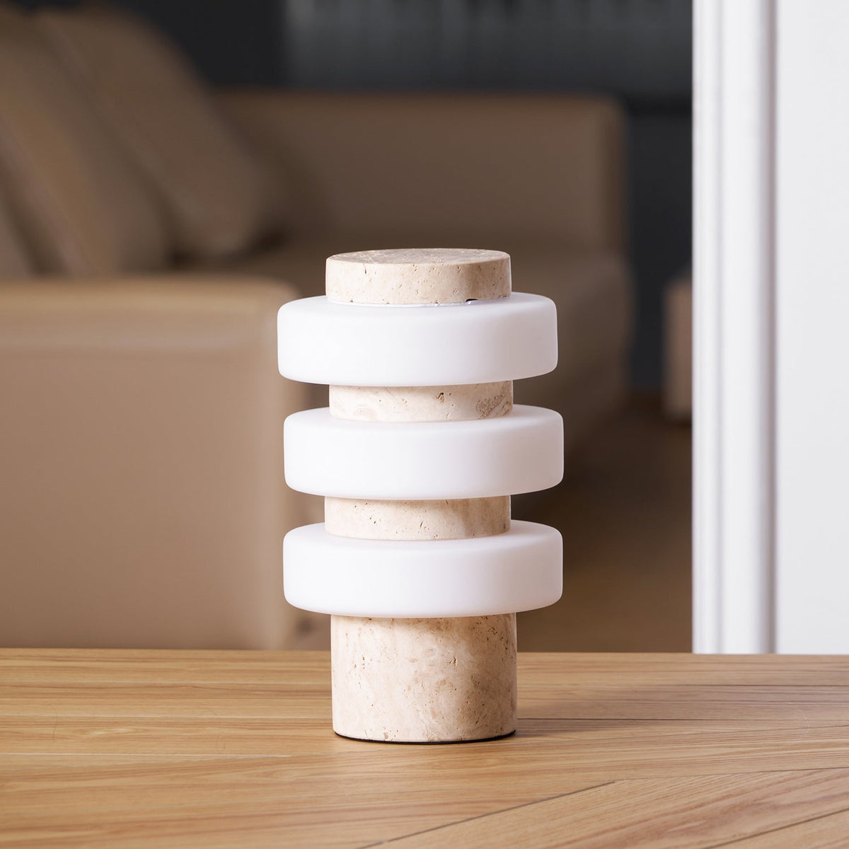 Close-up of the unlit Clérachic travertine table lamp against a plain backdrop, showing the stacked ring shade.
