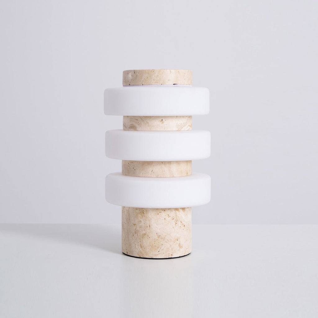 Studio shot of the unlit Clérachic travertine table lamp on white, viewed from a slight side angle.