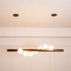 Linear walnut pendant light with soft glowing glass globes