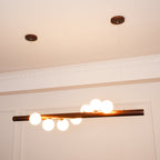 Walnut wood pendant bar with evenly spaced opal glass globes