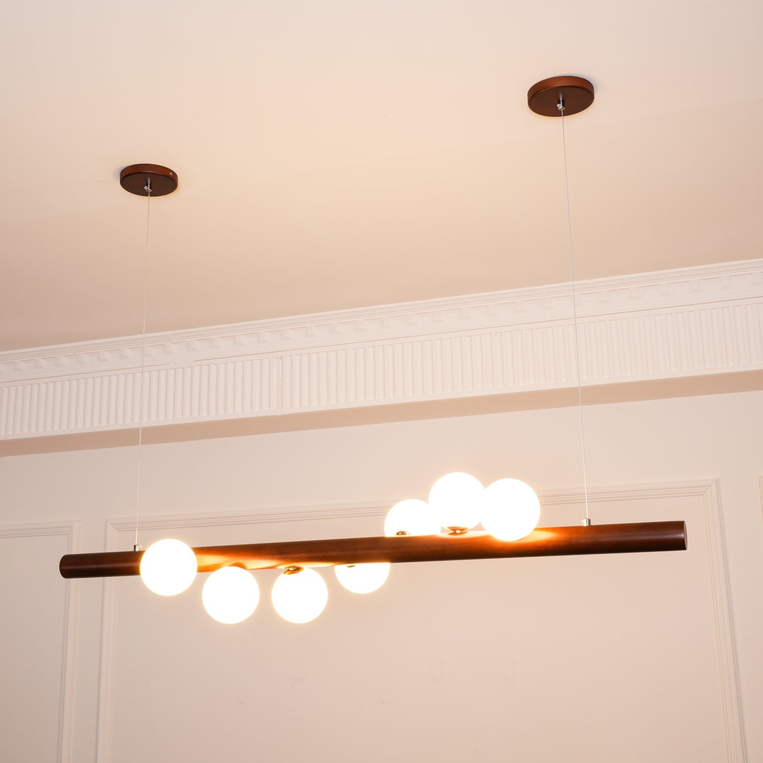 Walnut wood pendant bar with evenly spaced opal glass globes