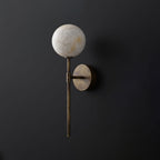 Another cutout shows this Clérachic wall sconce in brass, its ball shade lit against a dark backdrop.