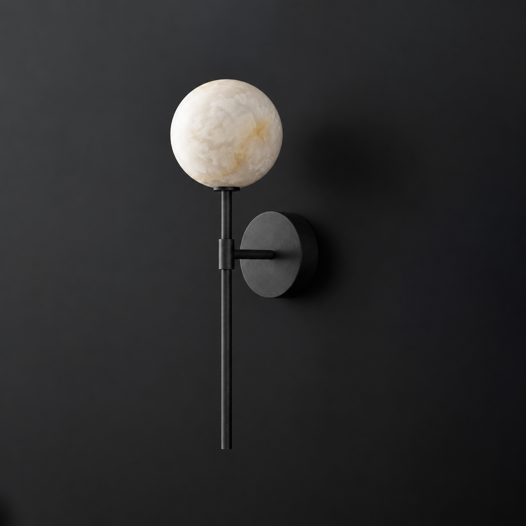 Cutout view of this Clérachic wall sconce in black, its alabaster ball shade glowing against a dark wall.
