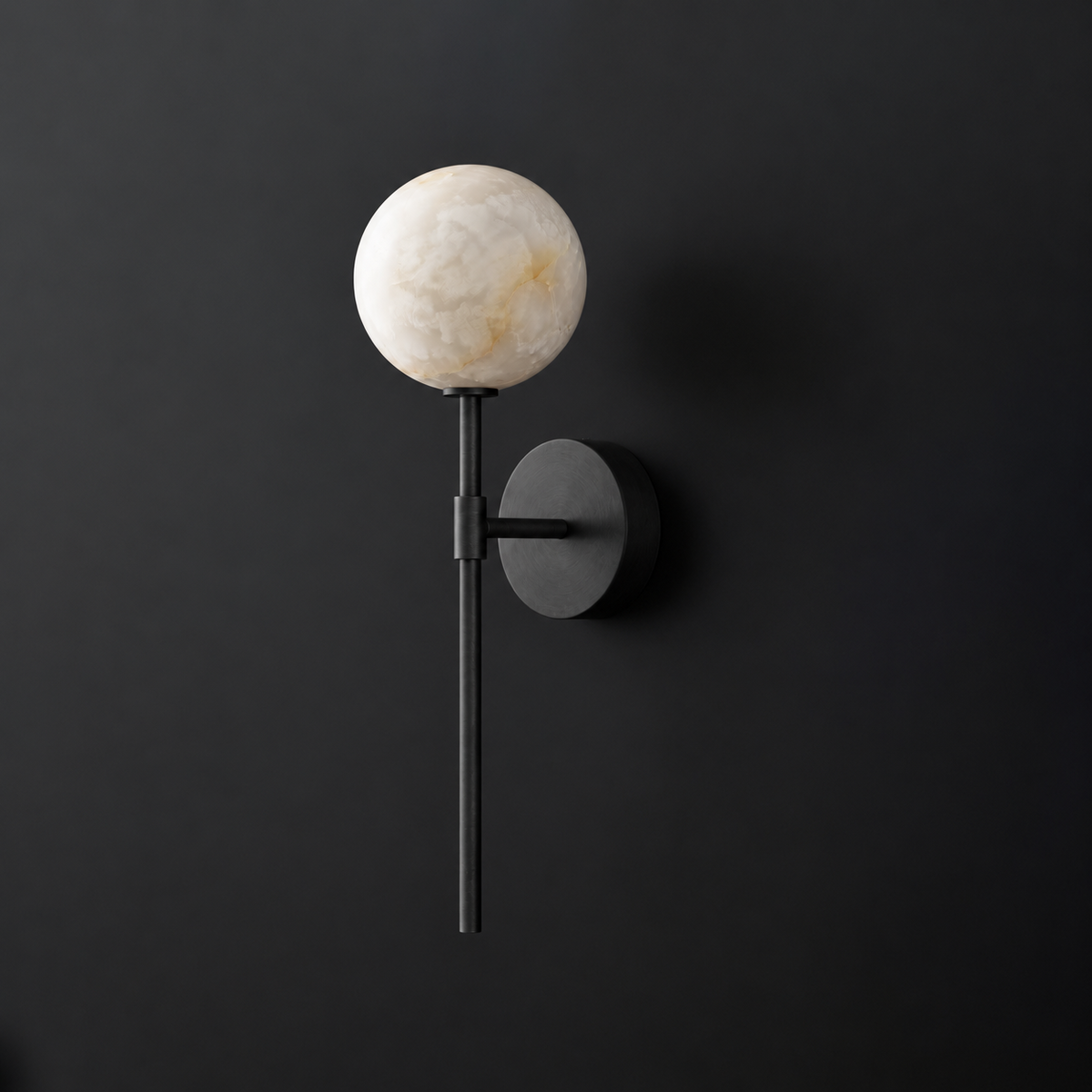 Cutout view of this Clérachic wall sconce in black, its alabaster ball shade glowing against a dark wall.