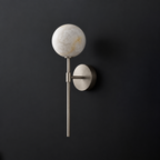 Cutout view of this Clérachic wall sconce in nickel, its rod and ball shade lit against black.