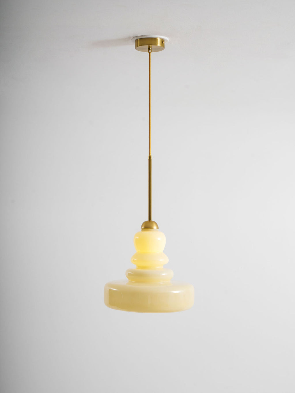Beige schoolhouse glass pendant glowing over a workspace
