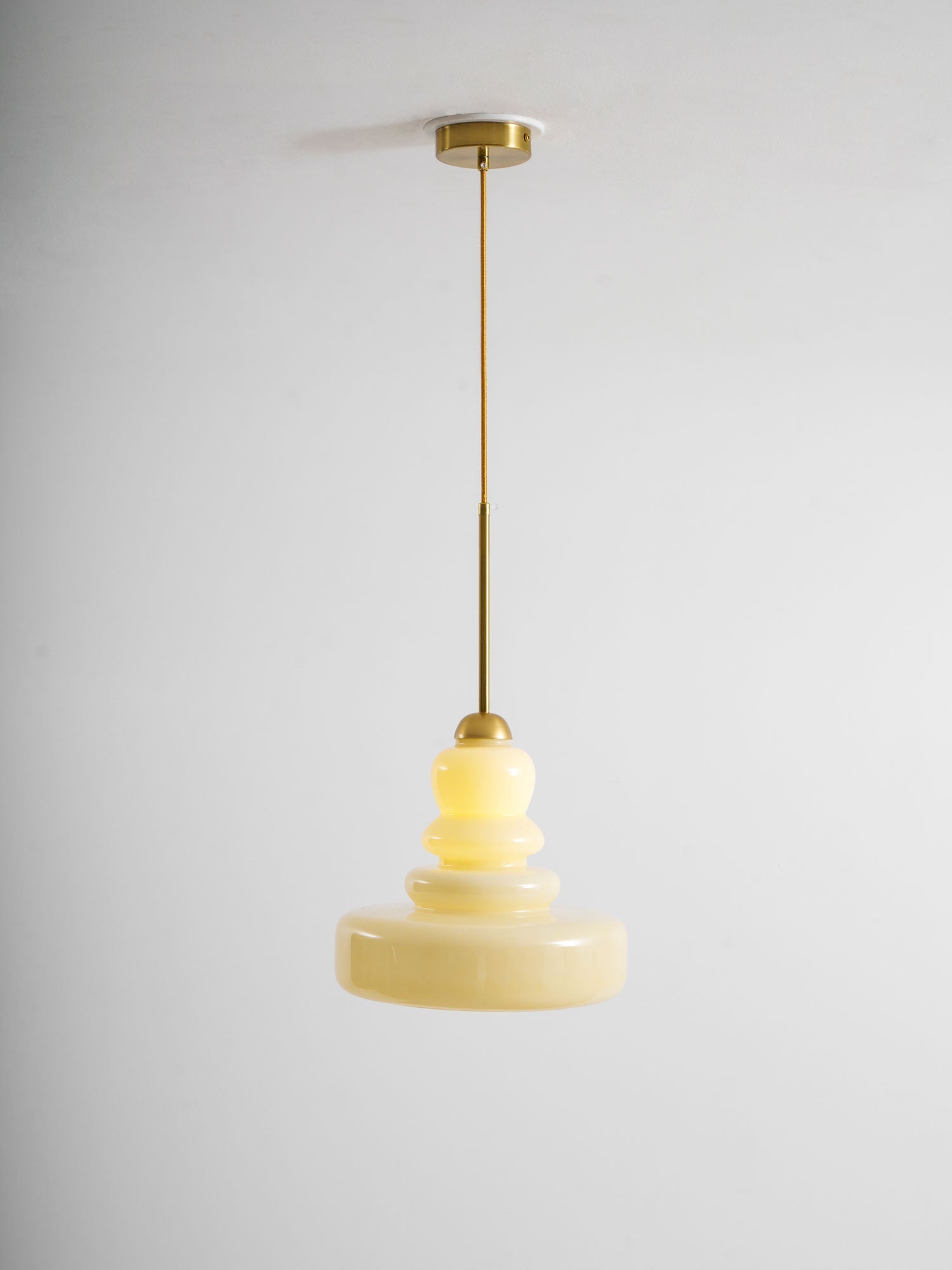 Beige schoolhouse glass pendant glowing over a workspace