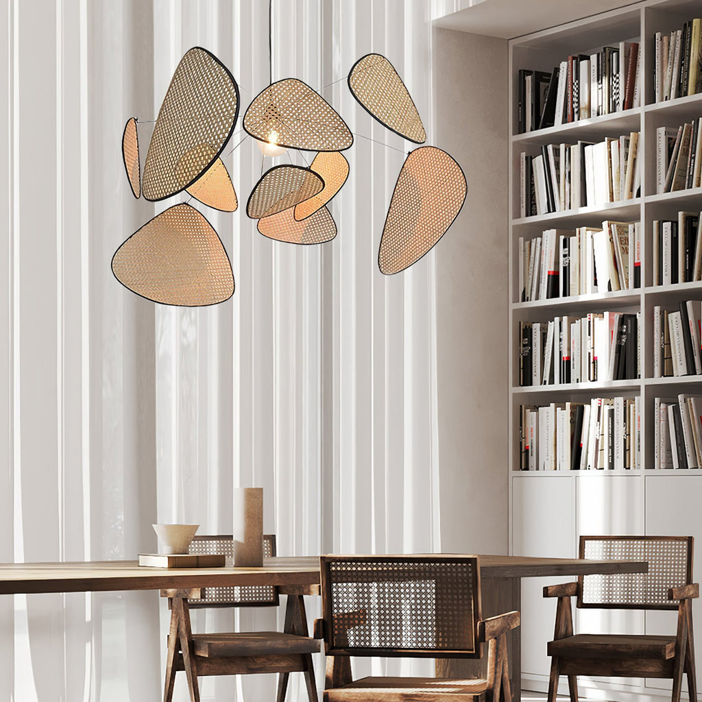 Beside a tall bookshelf, this Clérachic pendant's black frame and bamboo-weave paddles hang above a rustic wood table.