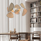 Beside a tall bookshelf, this Clérachic pendant's black frame and bamboo-weave paddles hang above a rustic wood table.