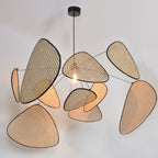 A wide studio angle shows this Clérachic pendant's paddles fanned out around the lit bulb, against a plain grey backdrop.