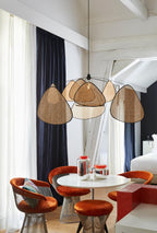 Under a sloped white ceiling, this Clérachic pendant hangs low over a round table ringed with rust-orange stools.