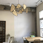 This Clérachic pendant hangs beneath an exposed concrete beam in a room with open wood shelving and a birdcage ornament.