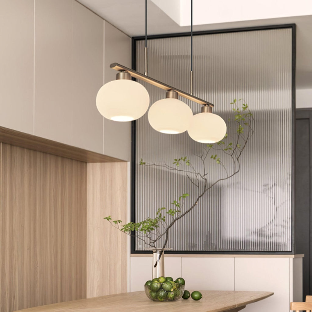 Three-globe linear pendant light over a contemporary table