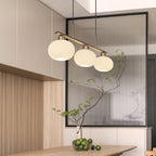 Three-globe linear pendant light over a contemporary table