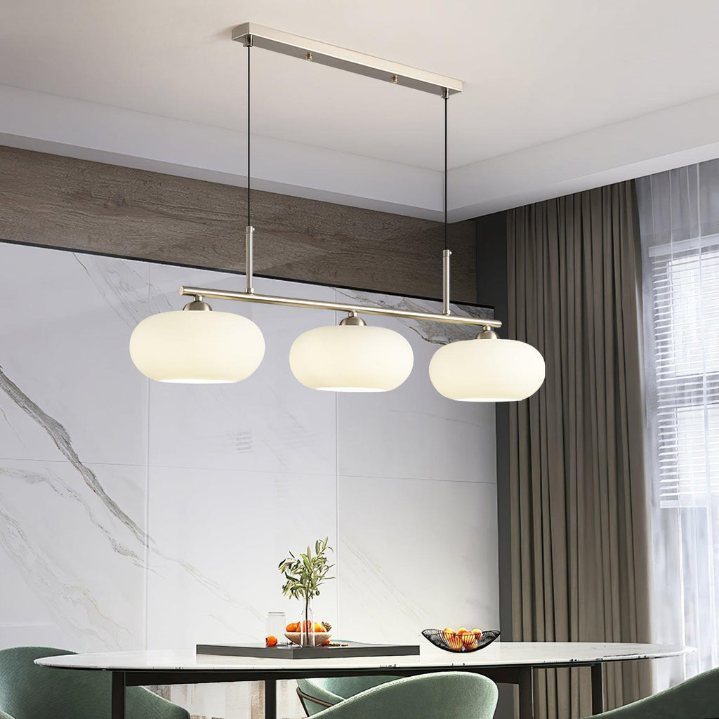 White glass globe shades on a slim linear pendant bar