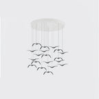 A dense cluster of black bird-shaped pendants from this Clérachic fixture hangs from a round white canopy on a plain backdrop.