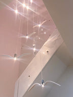 Bird-shaped pendants from this Clérachic light hang down a stairwell, with pinpoints of light sparkling above.
