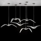 White bird-shaped pendants from this Clérachic fixture hang from a round white canopy against a black backdrop.