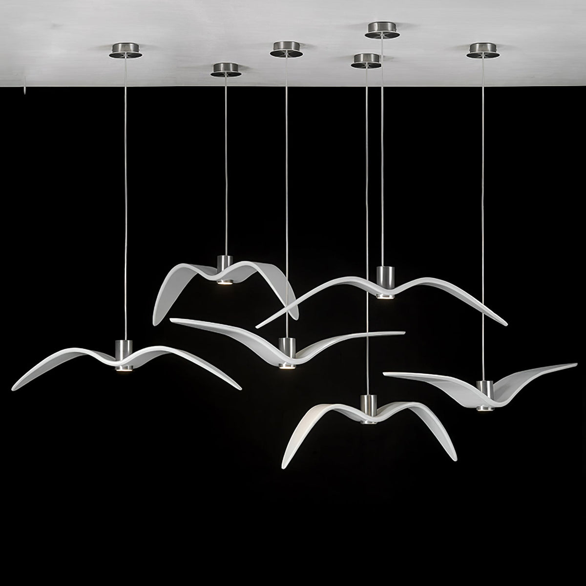 White bird-shaped pendants from this Clérachic fixture hang from a round white canopy against a black backdrop.