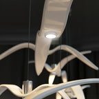 Close view of the glossy resin wings on this white Clérachic pendant, its LED lit warm from beneath.