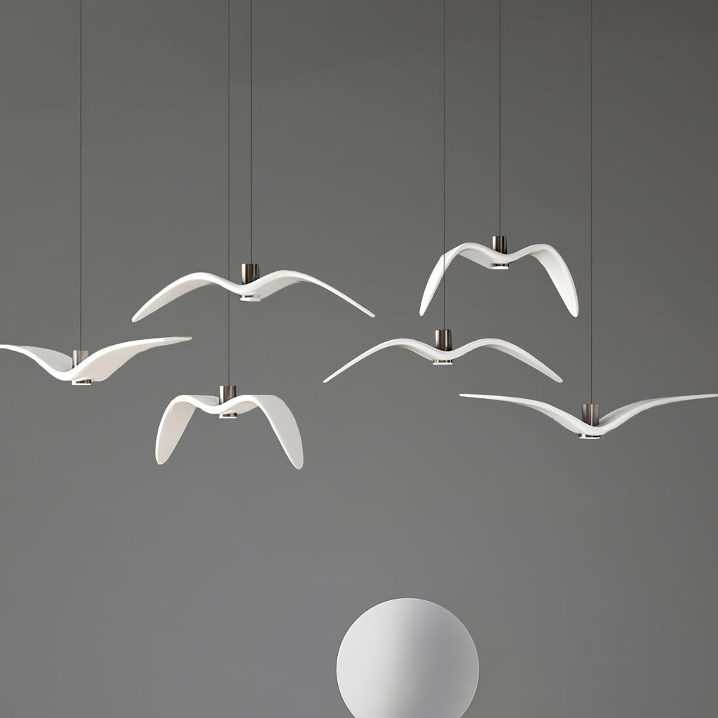 White bird-shaped pendants from this Clérachic fixture hang above a plain white sphere, on a grey backdrop.