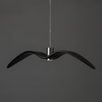 A black bird-shaped pendant from this Clérachic fixture hangs at a slightly different angle, on a plain dark-grey backdrop.