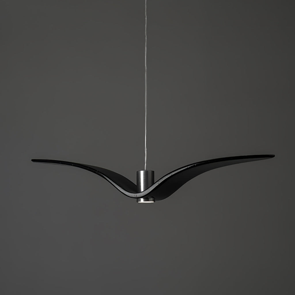 A black bird-shaped pendant from this Clérachic light hangs front-on with its wings at their widest, on a plain dark-grey backdrop.