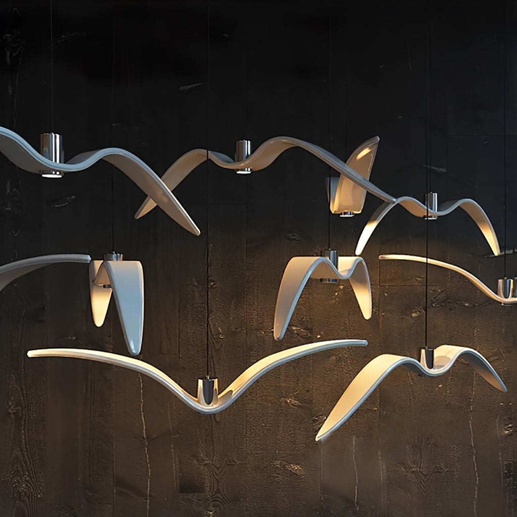 Lit bird-shaped pendants from this Clérachic fixture glow blue-white against a dark wood-panelled wall.