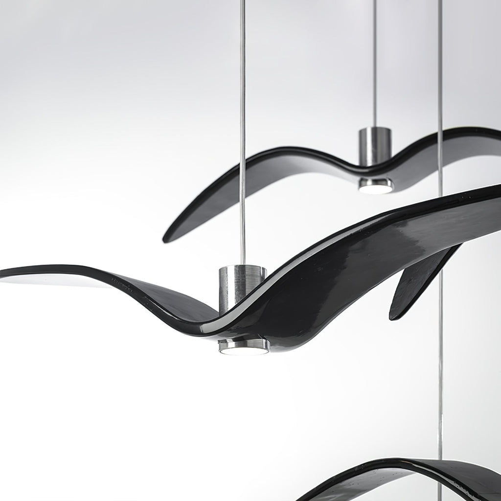 Close view of overlapping black bird-shaped pendants from this Clérachic fixture, their glossy resin wings crossing.
