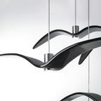 Close view of overlapping black bird-shaped pendants from this Clérachic fixture, their glossy resin wings crossing.