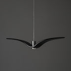 A black bird-shaped pendant from this Clérachic light hangs front-on, on a plain dark-grey backdrop.