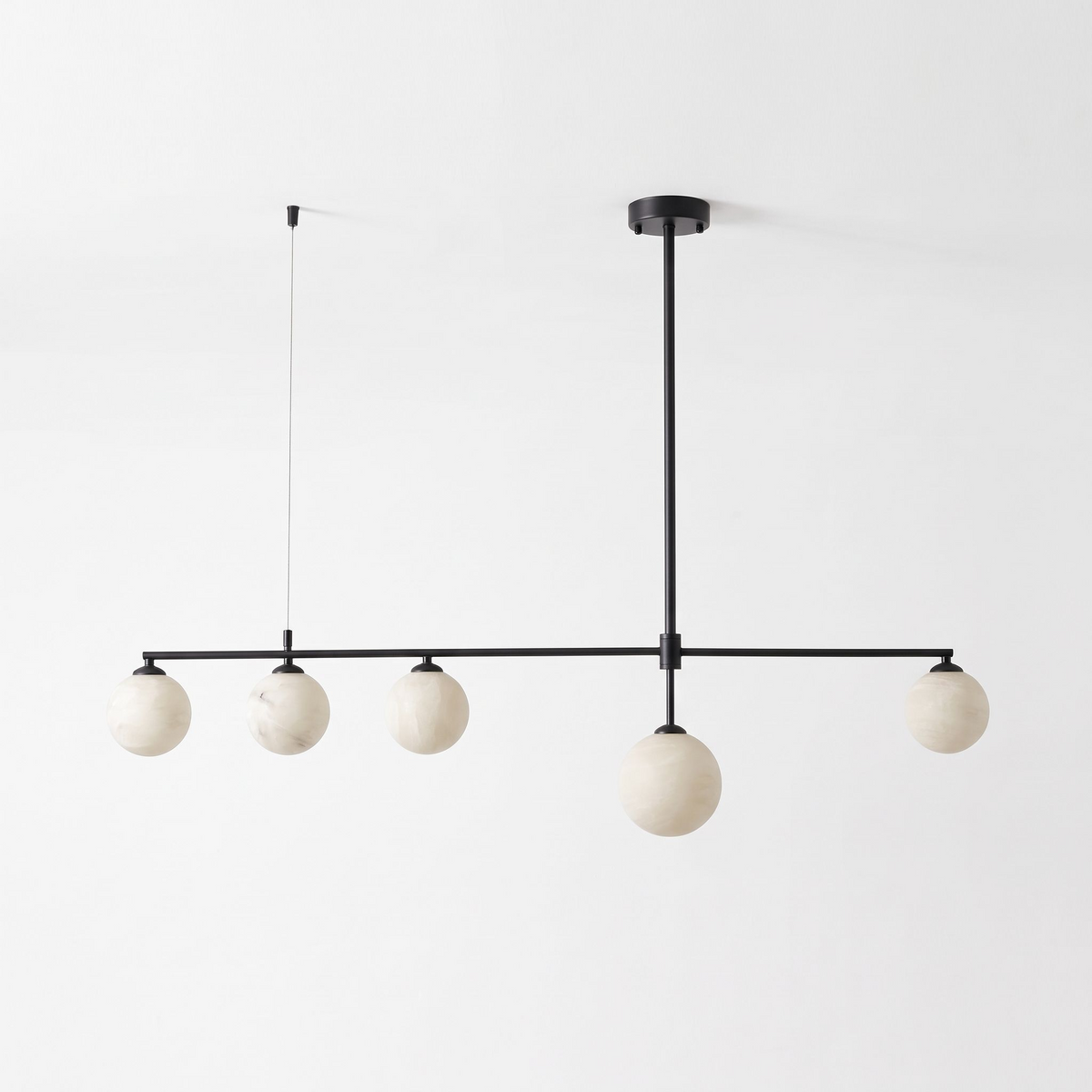 This matte black Clérachic chandelier stands unlit on a plain white background, its five alabaster balls in a row.